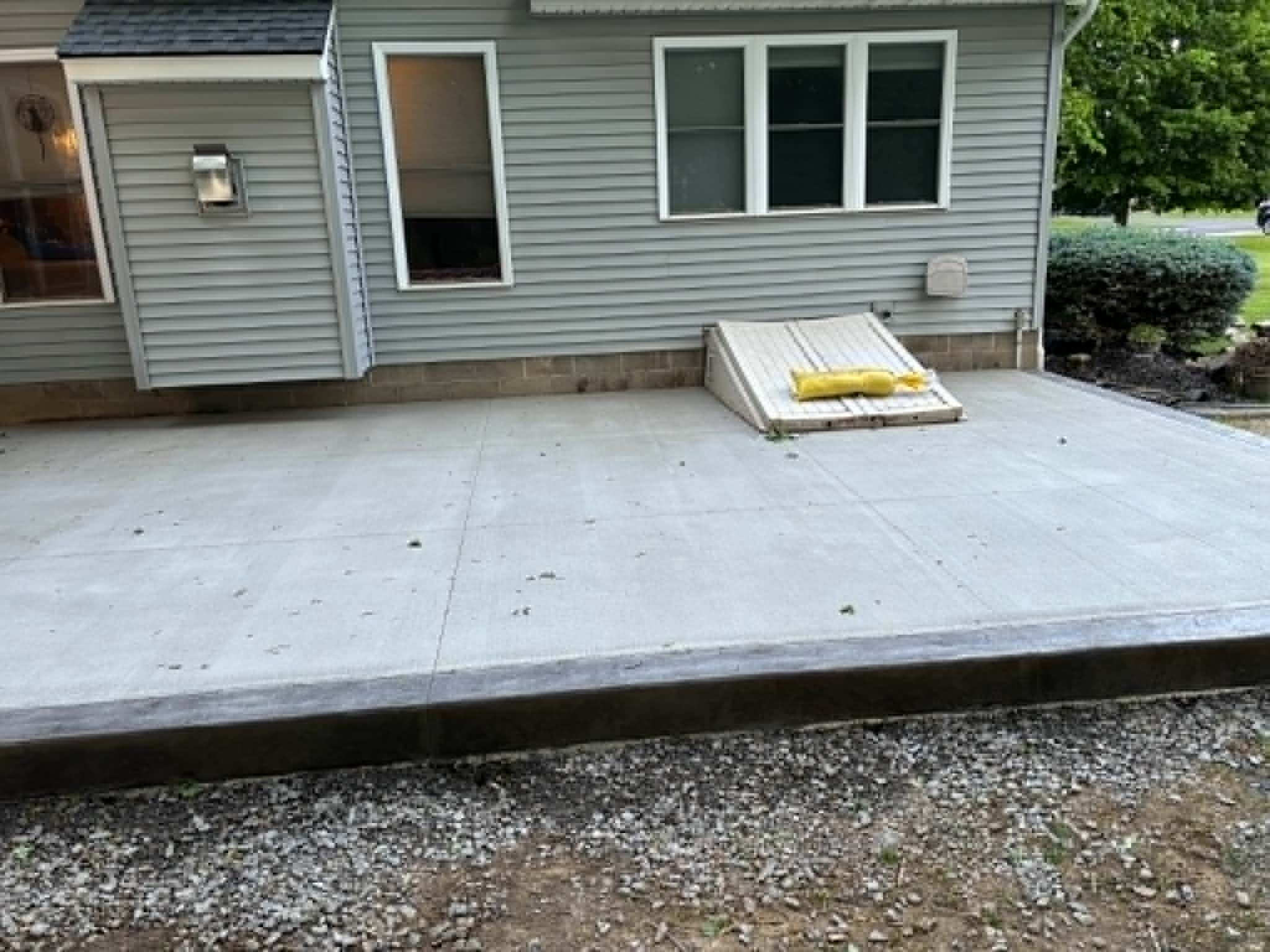 Broom-finish concrete patio field poured around a sloped basement cellar entry hatch in Webster NY